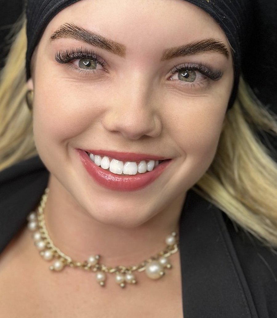 Cliente sorrindo com sobrancelhas desenhadas